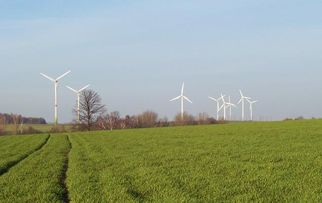 Mehrere Windkraftanlagen auf einem grünen Feld
